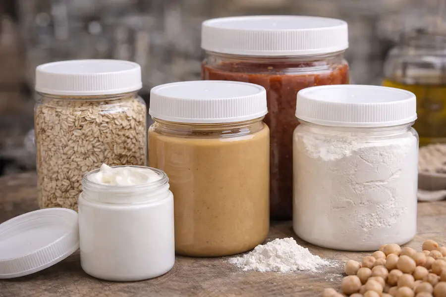 Tarros de plástico grado alimenticio con productos sólidos y pastas para uso industrial y alimentario.